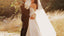 bride and groom hugging in field of golden grass and holding set of wedding vow books