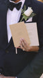 bride holding camel his wedding vow book and cream her wedding vow book against groom's tuxedo